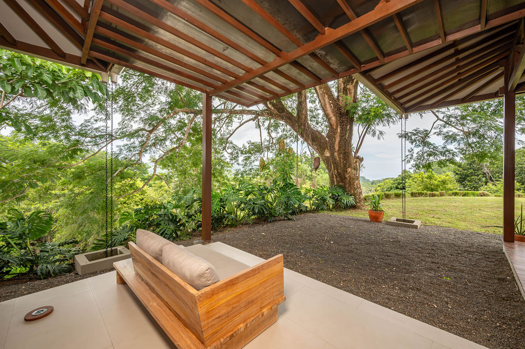Primary bedroom terrace with timber daybed and swings beneath an old-growth tree