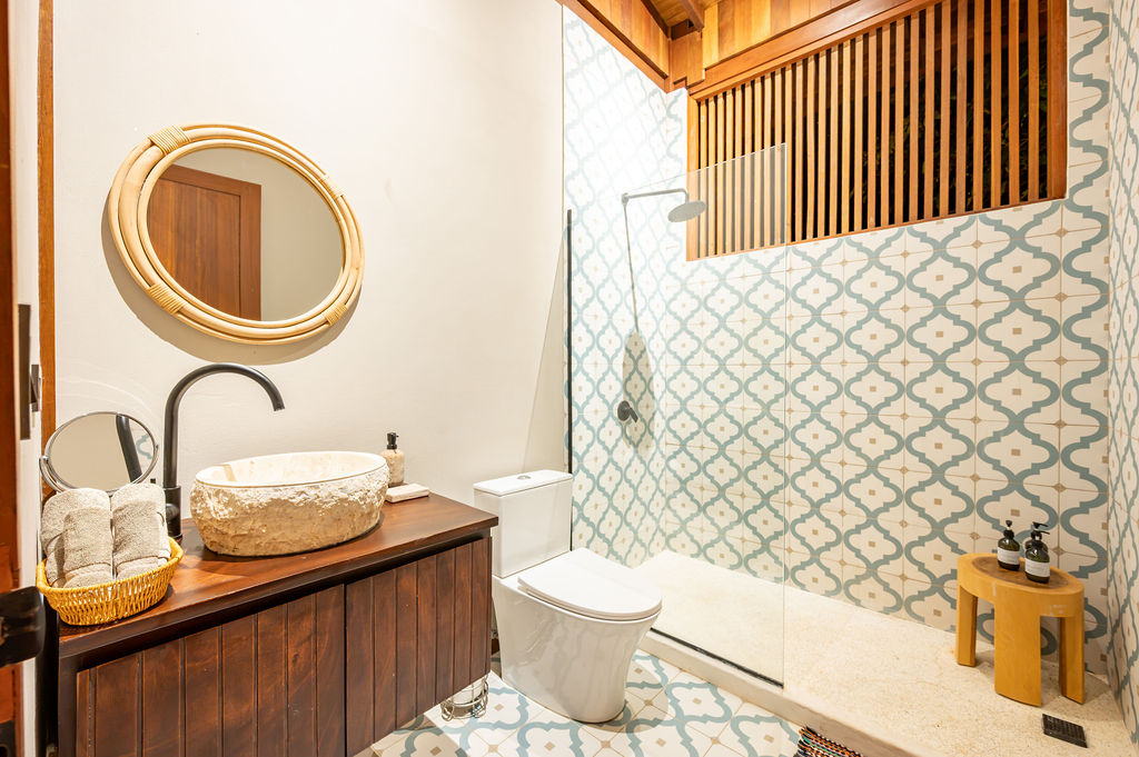 Shared bathroom with stone vessel basin and blue patterned tile shower