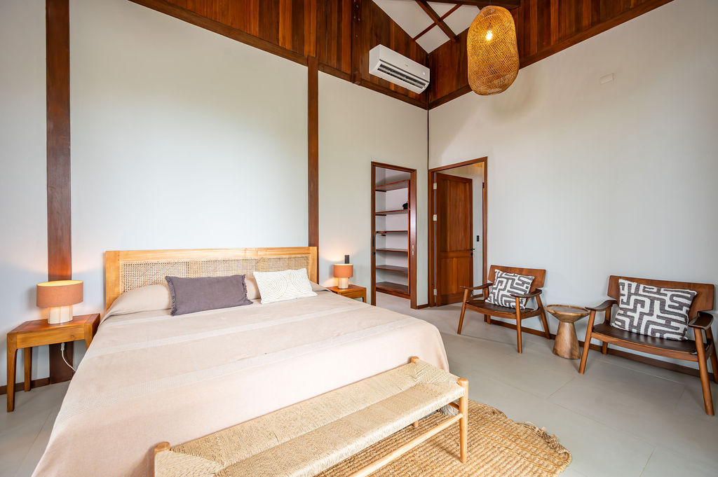 Primary bedroom wide view with neutral linens and high ceiling