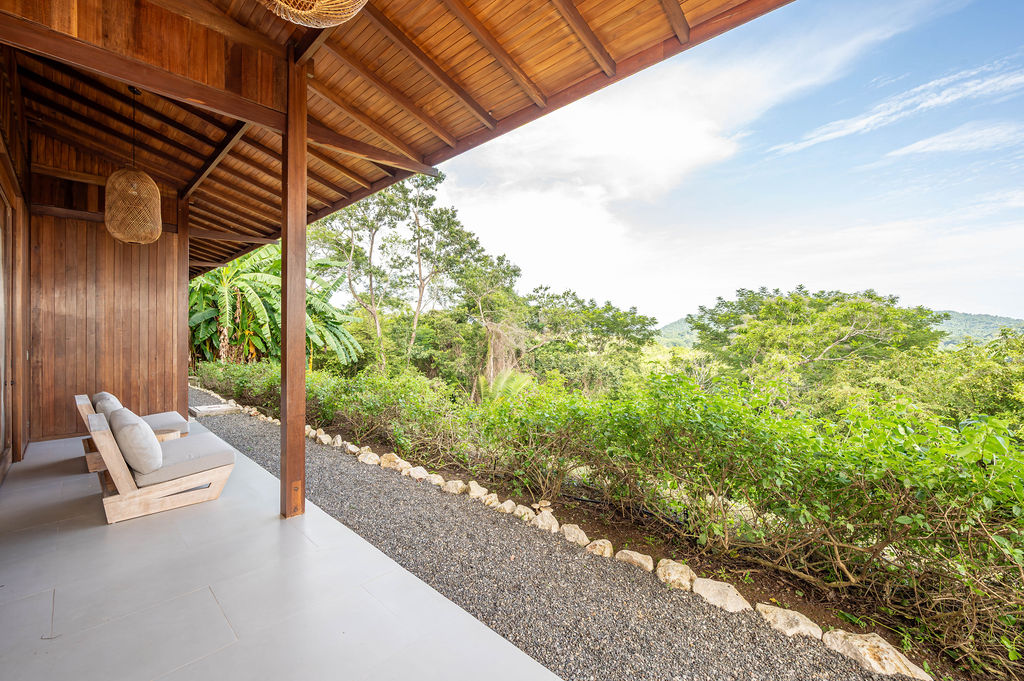 Bedroom one covered terrace with daybed and hillside outlook