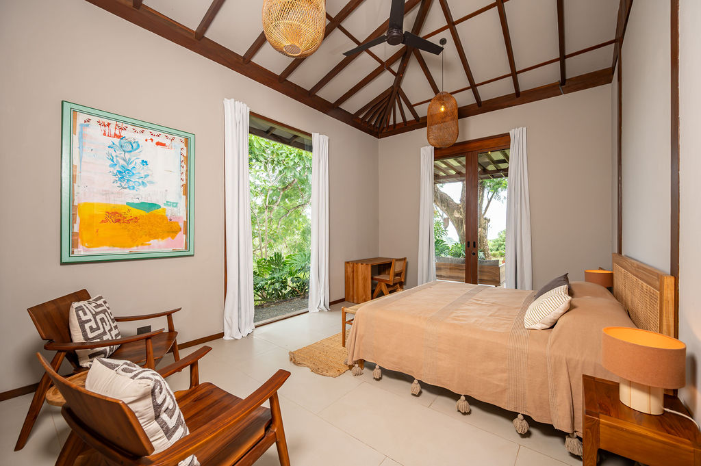 Primary bedroom with abstract artwork and woven lounge chairs