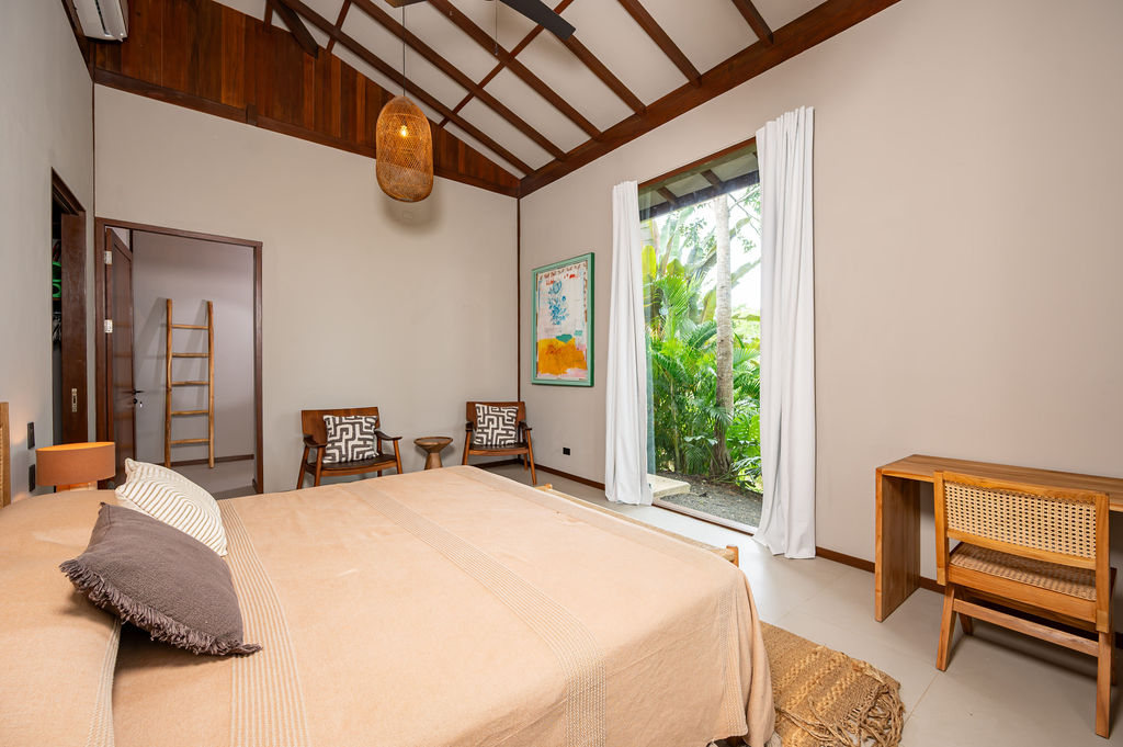 Primary bedroom with timber writing desk and view into the adjoining room