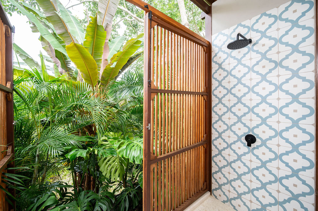 Outdoor shower reverse angle with decorative tiling and jungle backdrop