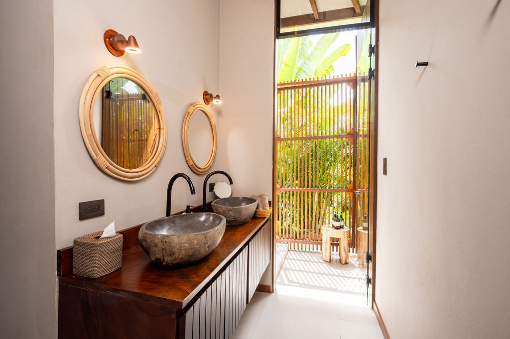 Bedroom two bathroom with stone basins, rattan mirrors and warm timber tones