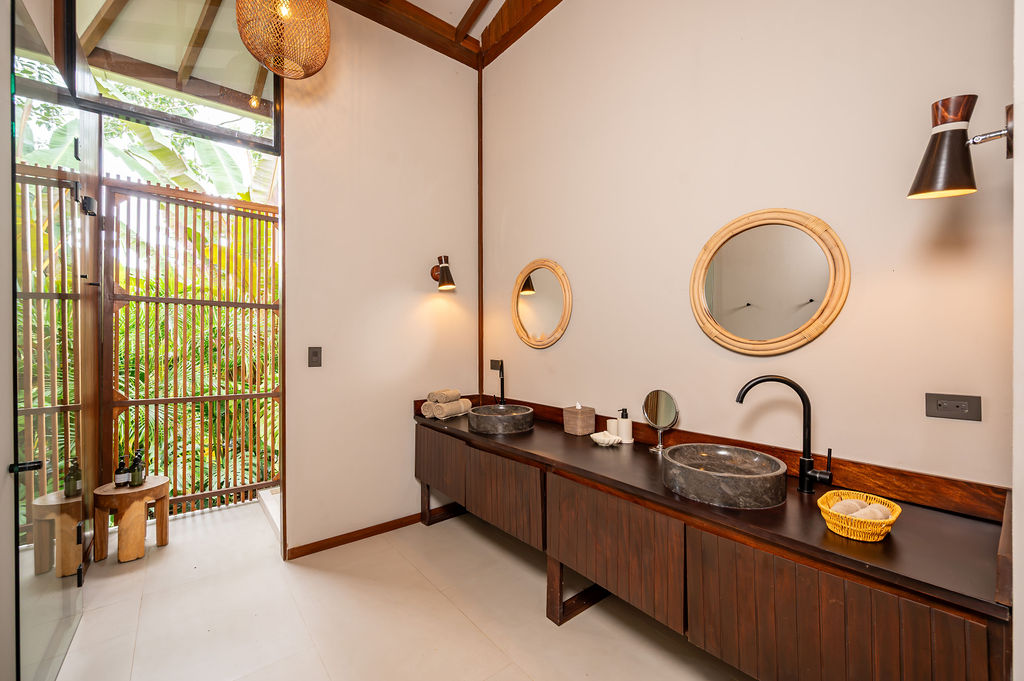 Primary bathroom with twin stone vessel sinks, rattan mirrors and slatted timber screen